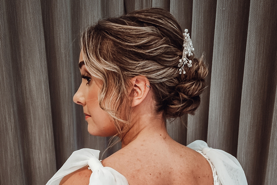 View of brides wavy updo with accessory from back